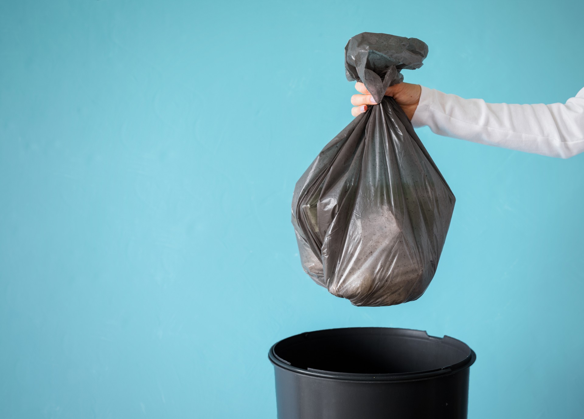 Hand holding garbage in plastic bag